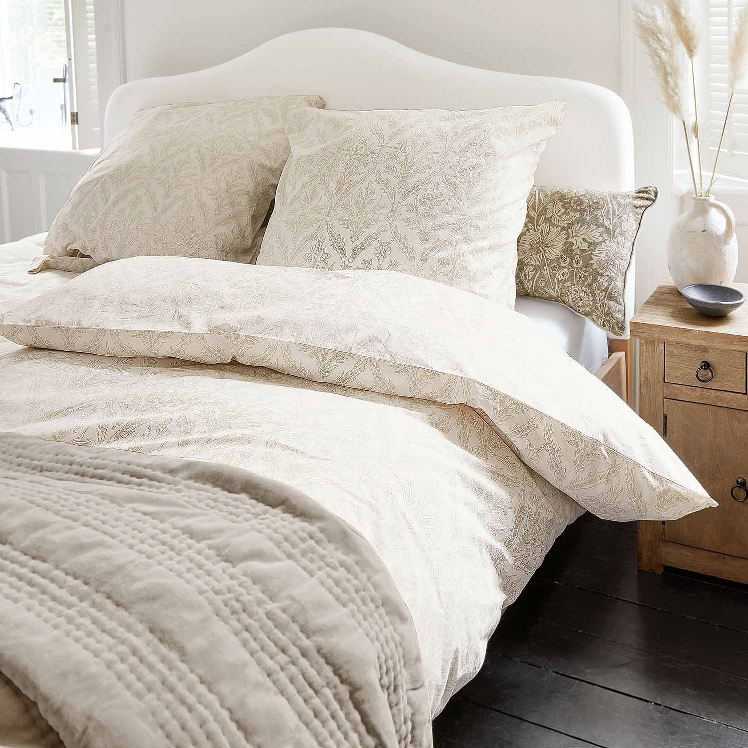 Světle bavlněné povlečení s jemným rostlinným vzorem a měkká deka v útulné ložnici