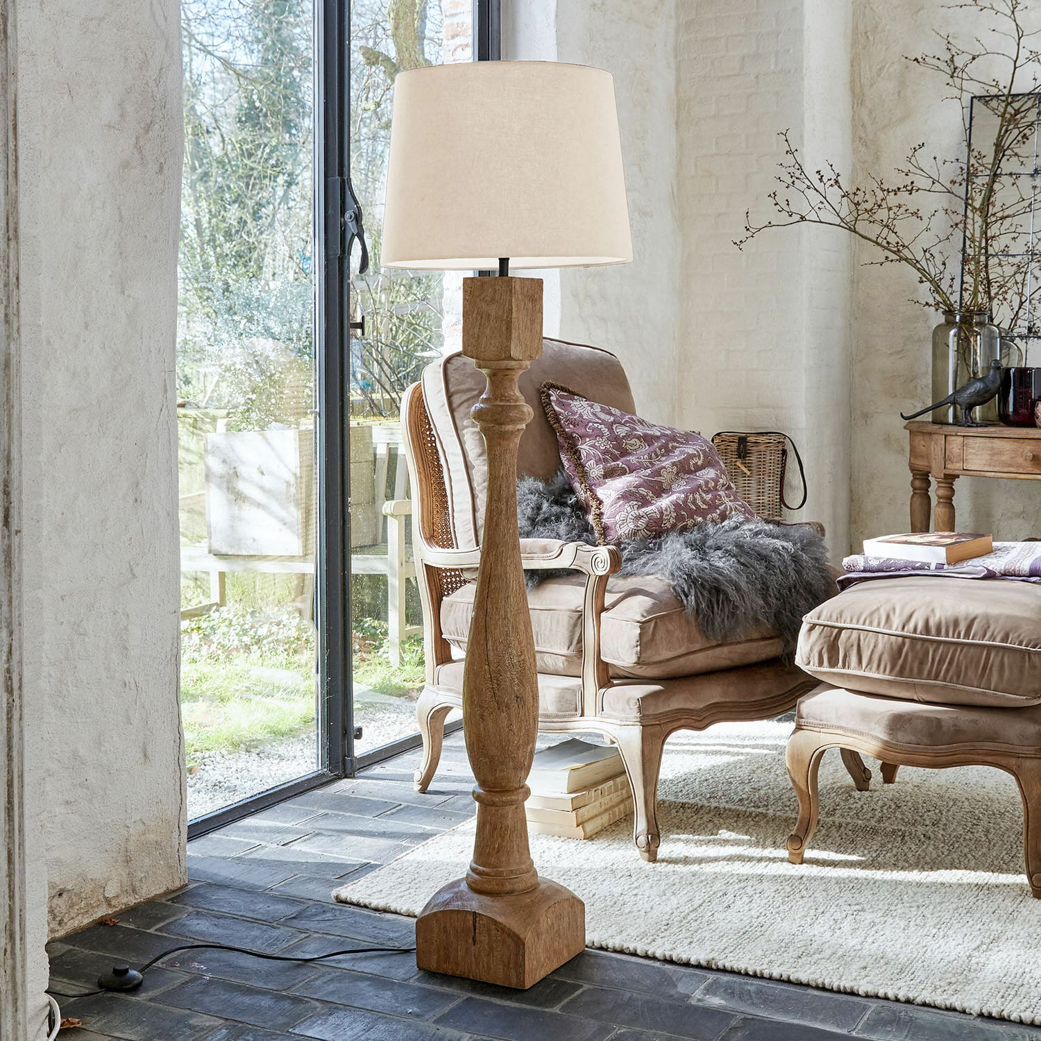 Stojací lampa Fernisto Dřevěná stojací lampa s béžovým stínidlem v útulném obývacím pokoji s křesly a kobercem