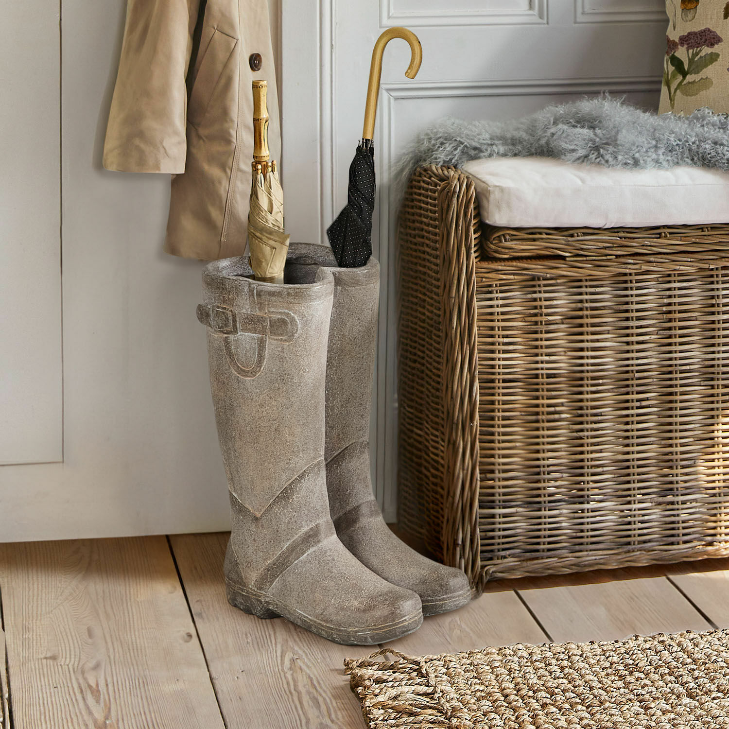Šedé gumové holínky u dveří s deštníky a proutěnou lavicí v pozadí