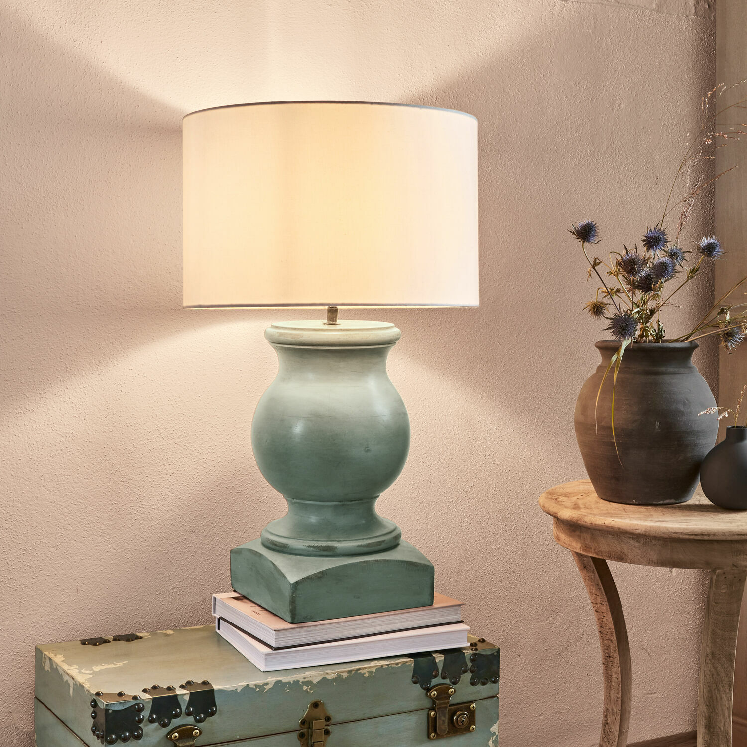 Stolní lampa Todd Stolní lampa ze zelené keramiky s béžovým stínidlem na starém kufru, interiérová dekorace