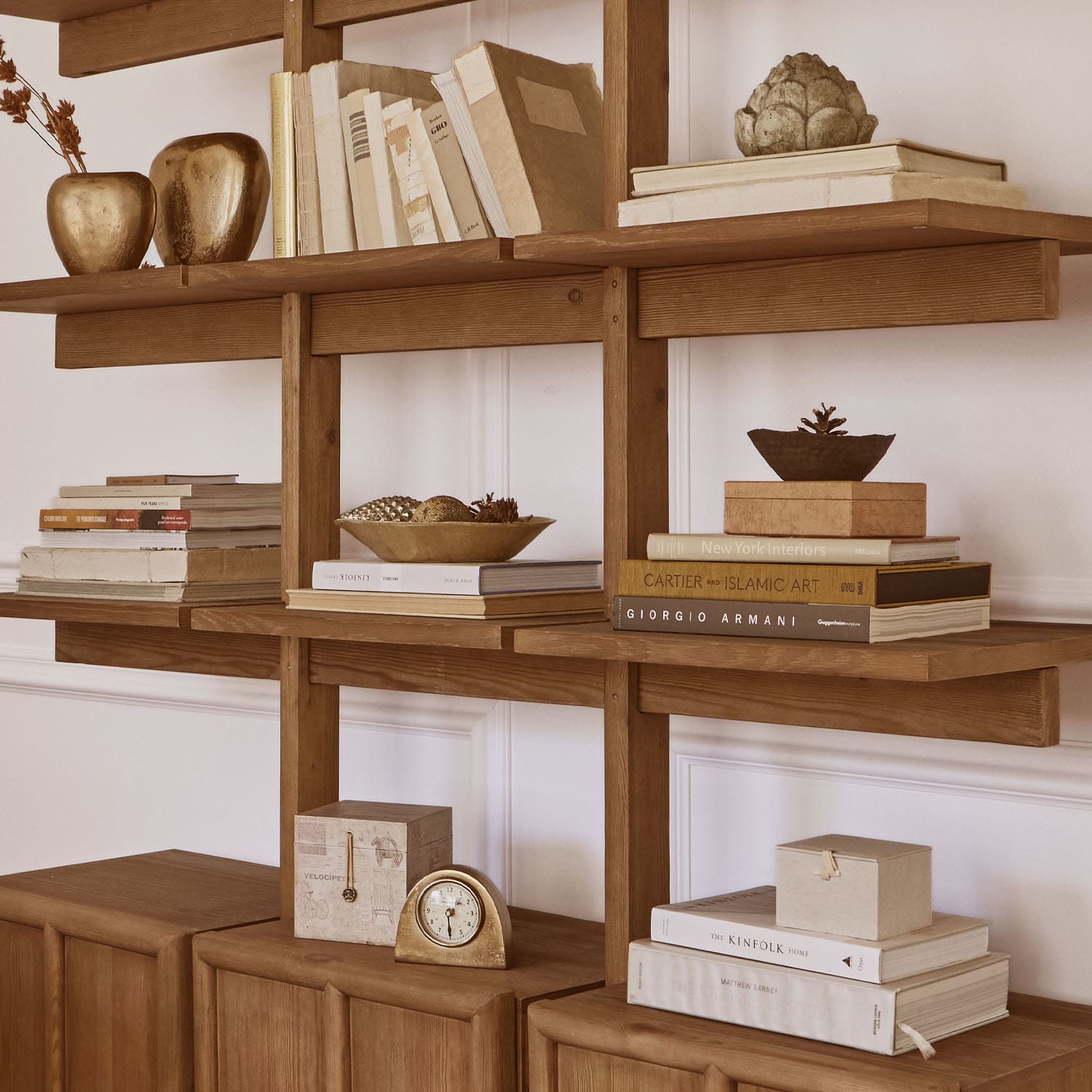 Dřevěný regál s knihami, zlatými dekoracemi a hodinami, elegantní interiérový design