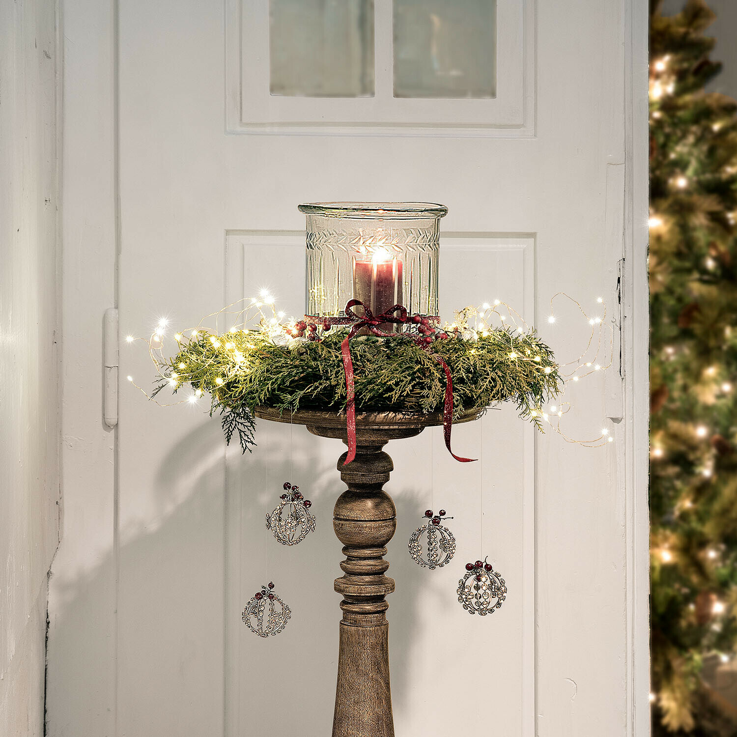 Dřevěný svícen s zeleným věncem, červenými stuhami a LED světýlky pro vánoční výzdobu